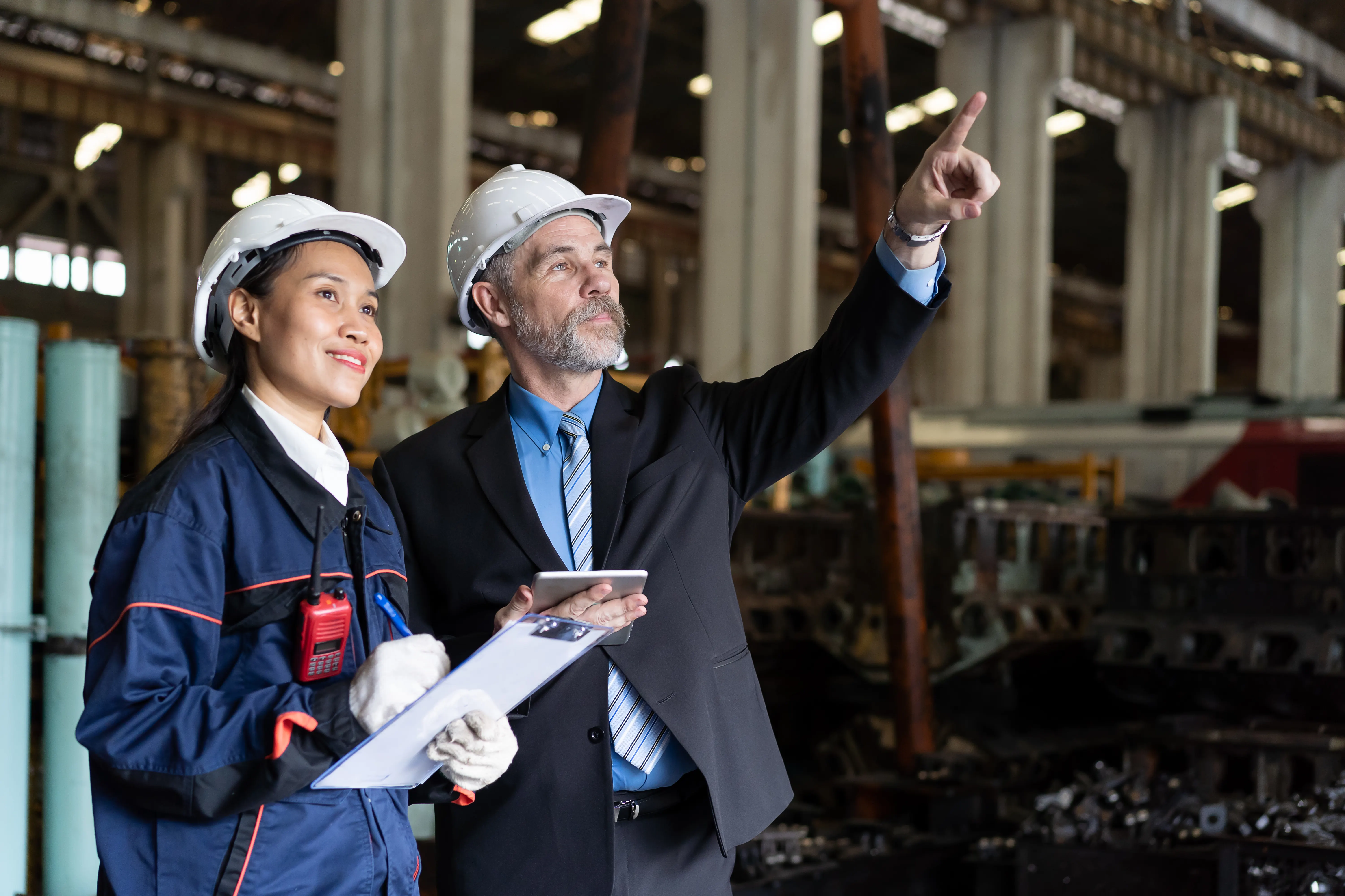 Two engineers in hard hats reviewing operations on an industrial facility floor