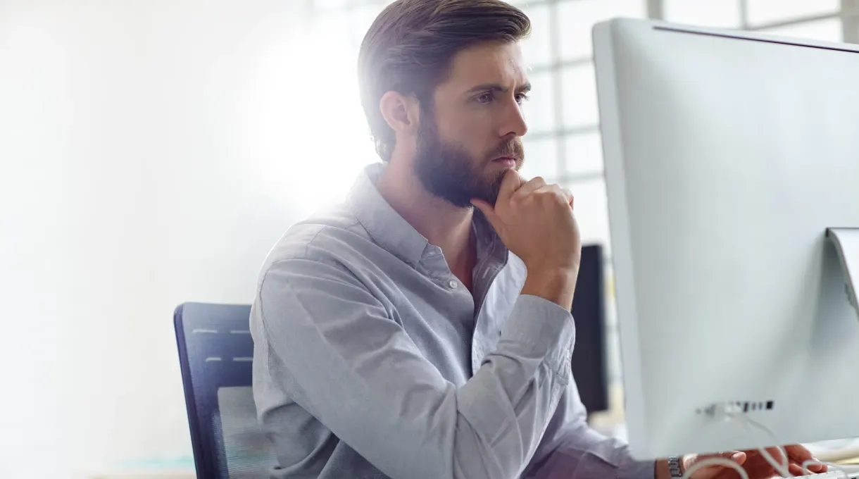 Facilities manager comparing software platforms on a desktop monitor