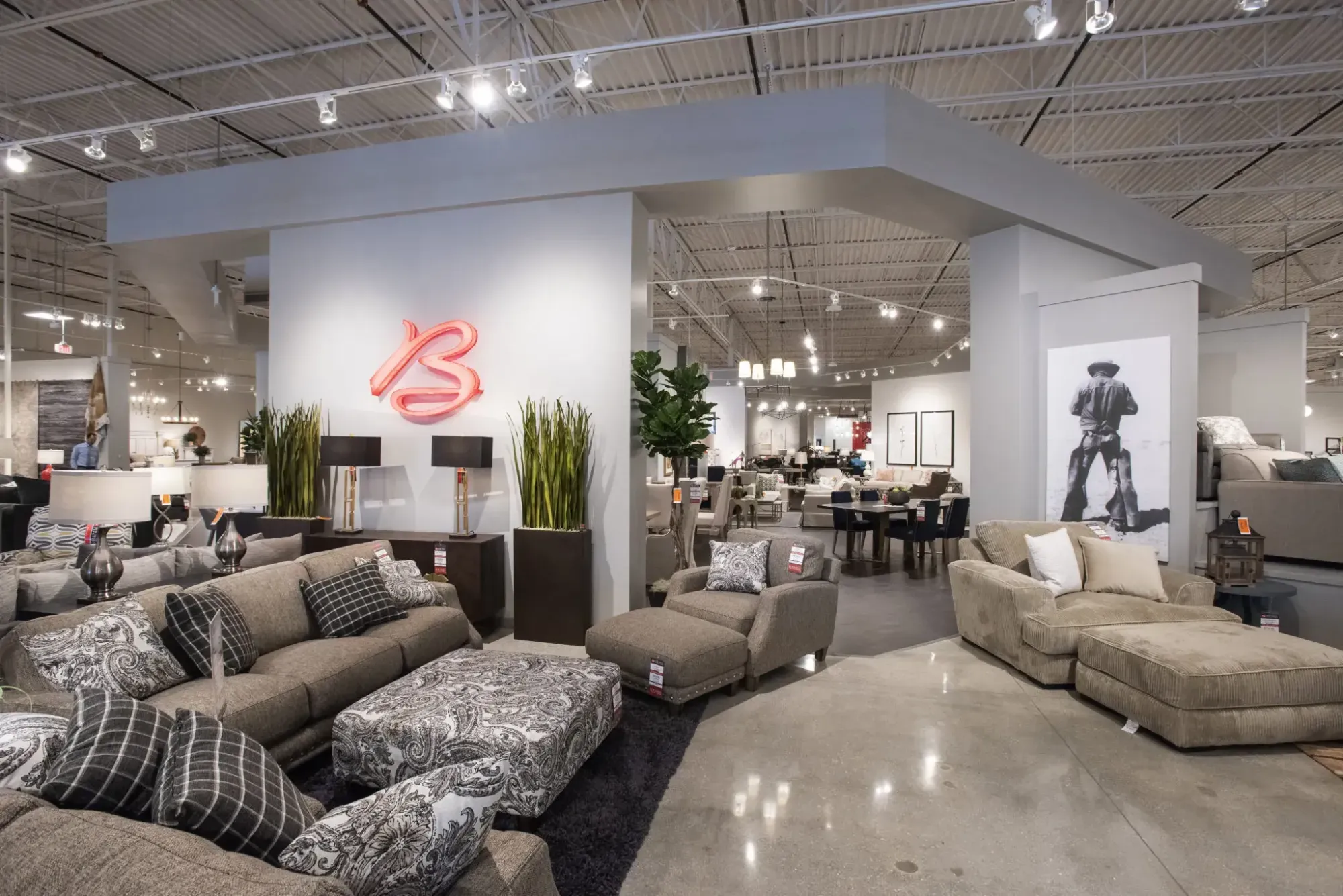 Sofas and accent chairs on display in a Bob Mills Furniture showroom beneath the red script B logo