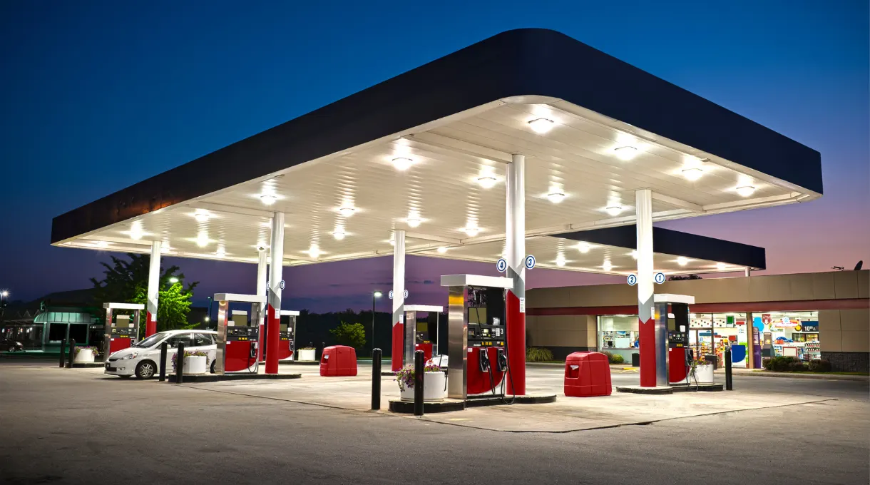 A convenience store's fuel pumps and canopy lit up at dusk