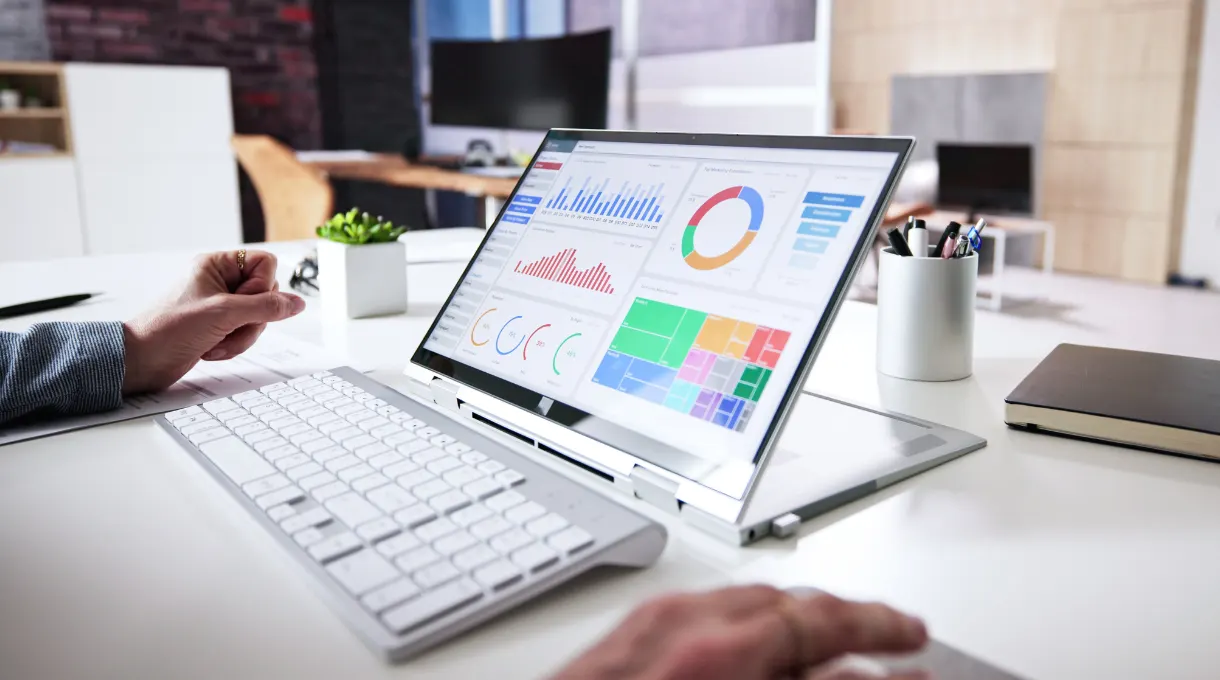 Laptop displaying a facility management KPI dashboard with charts and graphs
