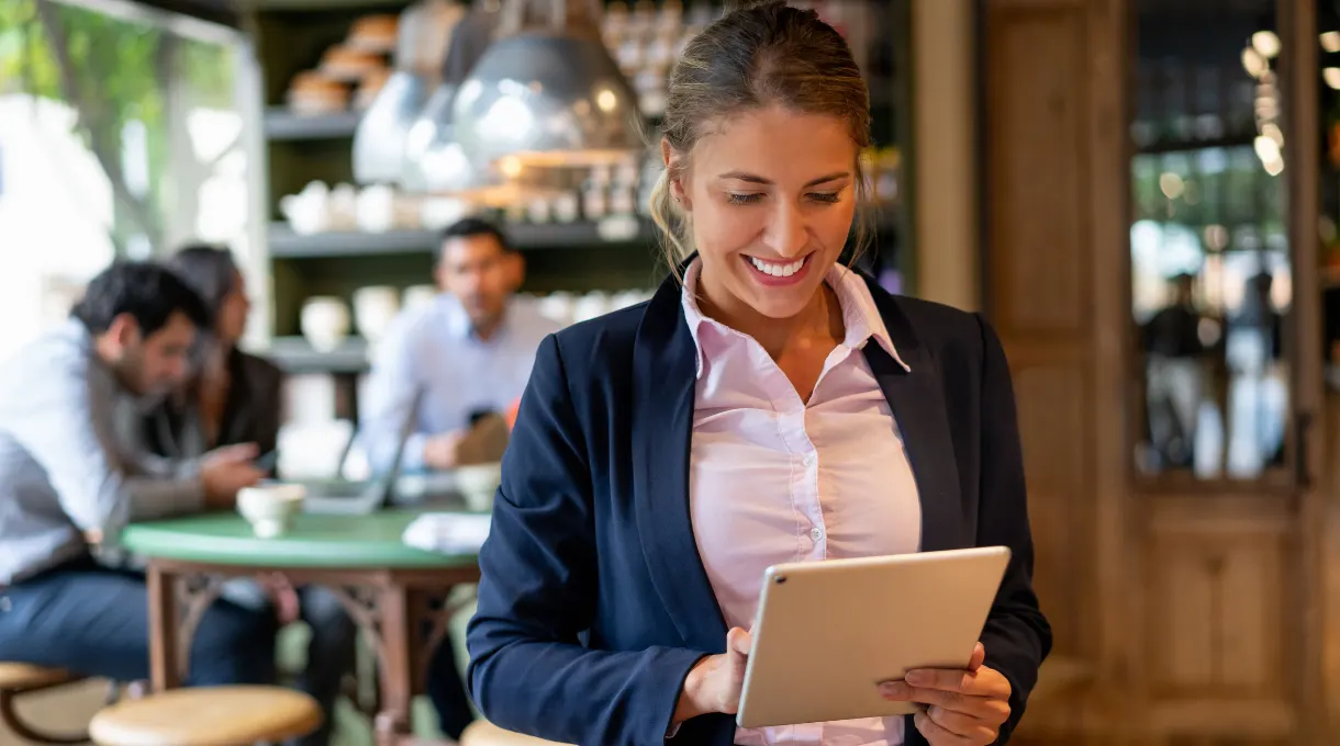 Restaurant manager reviewing a work order on a tablet in a restaurant dining area