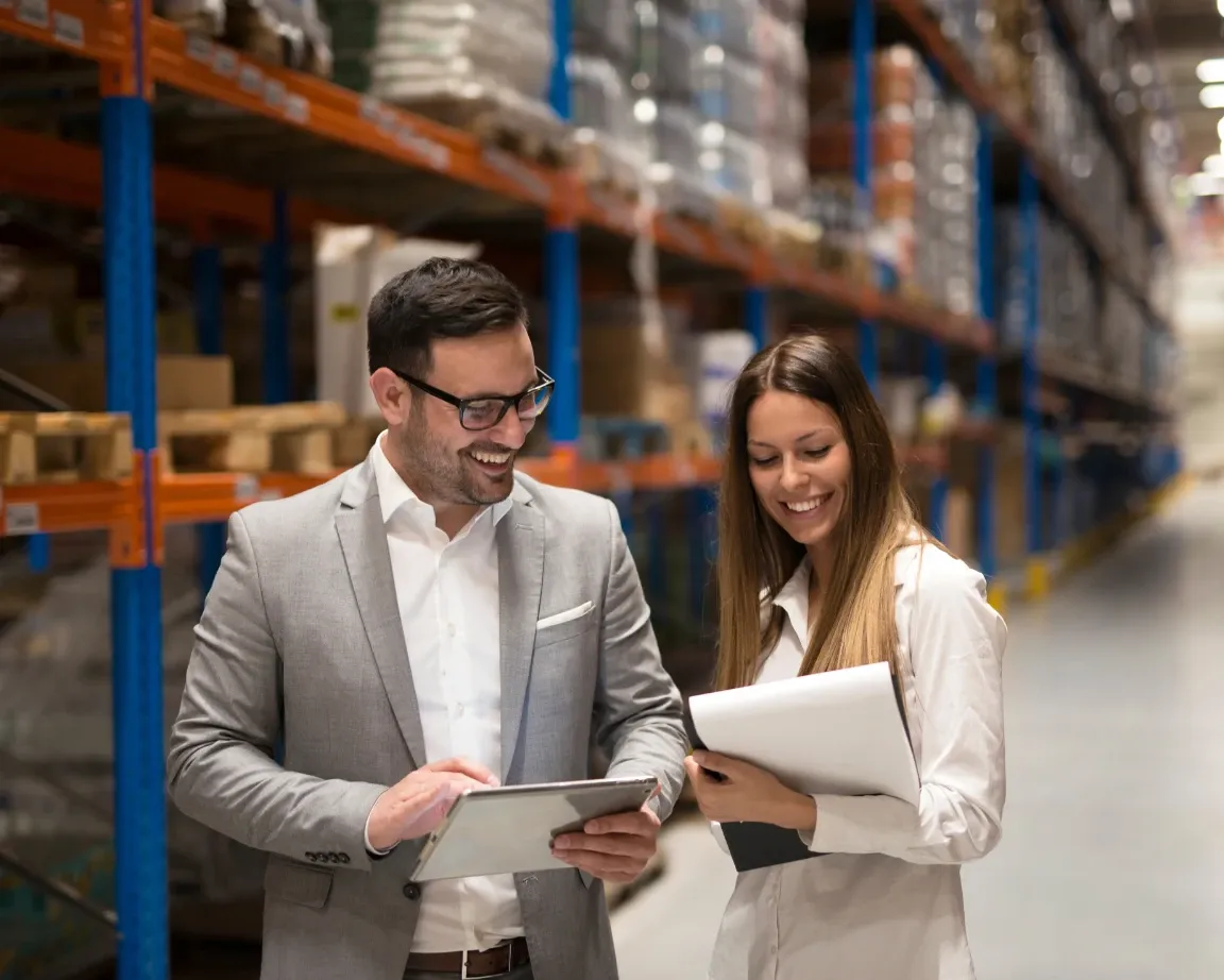 Two managers reviewing a tablet together in a warehouse aisle